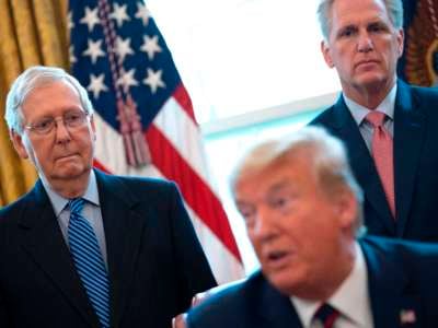 Mitch Mcconnell and Kevin McCarthy stand behind a seated Donald Trump