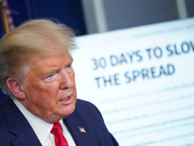 Donald Trump stands in front of a display reading "30 DAYS TO SLOW THE SPREAD"