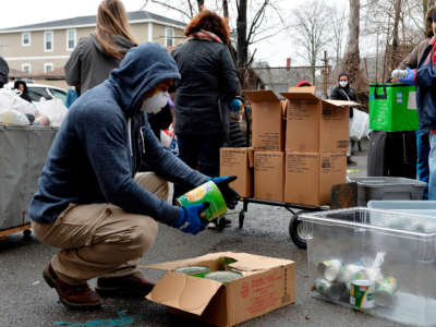 Volunteers hand out food and other goods to hundreds of people during the COVID-19 crisis in Everett, Massachusetts, on March 20, 2020.