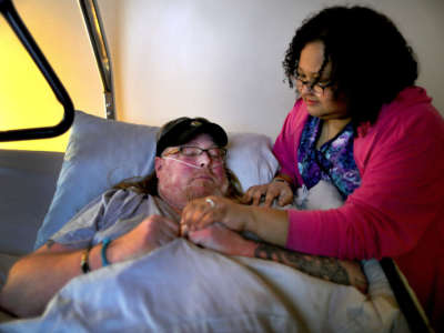 Melissa Baptista checks on her fiancé Eric McGuire, who is bedridden with several medical conditions and is on oxygen, in Franklin, Massachusetts, on March 25, 2020. Melissa is a nurse at a nearby nursing home and depends on caregivers to take care of his needs, but one caregiver plans to isolate herself because she has a sinus infection and will be tested for coronavirus.