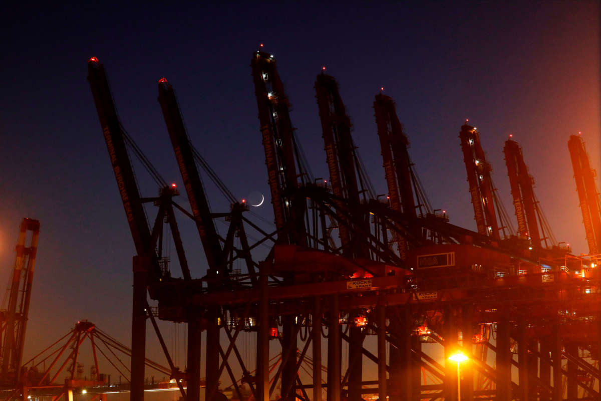 The waxing crescent moon is seen between dock levelers at a container terminal in the harbor of the northern German city of Hamburg on March 26, 2020. The lifeblood of globalization has been considerably affected over the course of the outbreak.