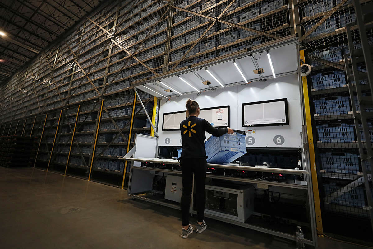 A walmart employee holds a box in a warehouse