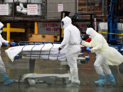 Medical personnel move a deceased patient to a refrigerated truck serving as a makeshift morgue at Brooklyn Hospital Center on April 9, 2020, in New York City.