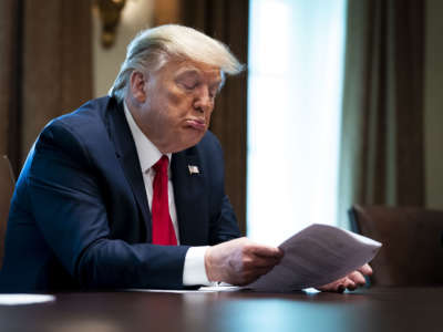 Donald Trump sits at a desk