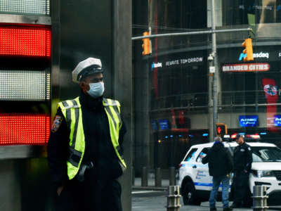 Police officers in face masks are seen near the NASDAQ stock exchange at the crossing of Broadway and West 43rd Street during the COVID-19 pandemic, April 12, 2020.