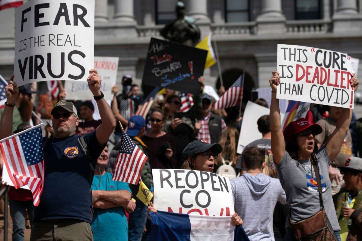 A bunch of people displaying the US flag protest outside a statehouse