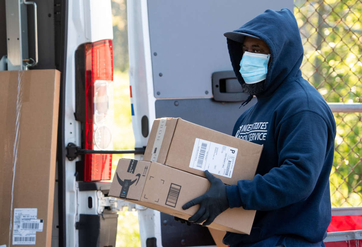 A mailman wearing a mask and gloves to protect himself and others from COVID-19 loads a postal truck with packages at a United States Postal Service post office location in Washington, D.C., April 16, 2020.