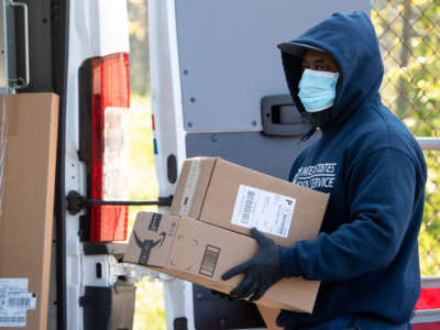 A mailman wearing a mask and gloves to protect himself and others from COVID-19 loads a postal truck with packages at a United States Postal Service post office location in Washington, D.C., April 16, 2020.