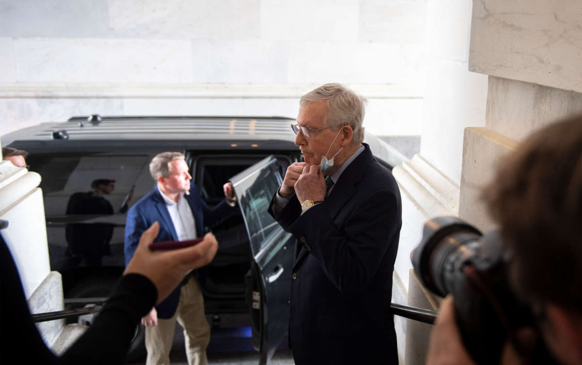 Senate Majority Leader Mitch McConnell pulls down his mask to talk to reporters after attending a pro forma session on the Senate floor in the Capitol on April 20, 2020.