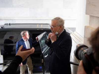 Senate Majority Leader Mitch McConnell pulls down his mask to talk to reporters after attending a pro forma session on the Senate floor in the Capitol on April 20, 2020.