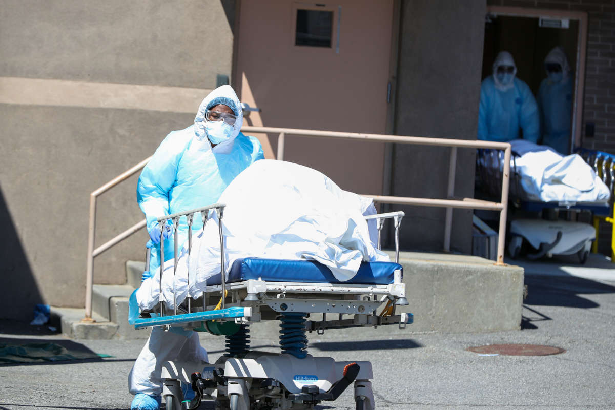 Health officials carry the body of a COVID-19 victim on a stretcher to container morgues by the Wyckoff Heights Medical Center in Brooklyn, New York City, on April 6, 2020.
