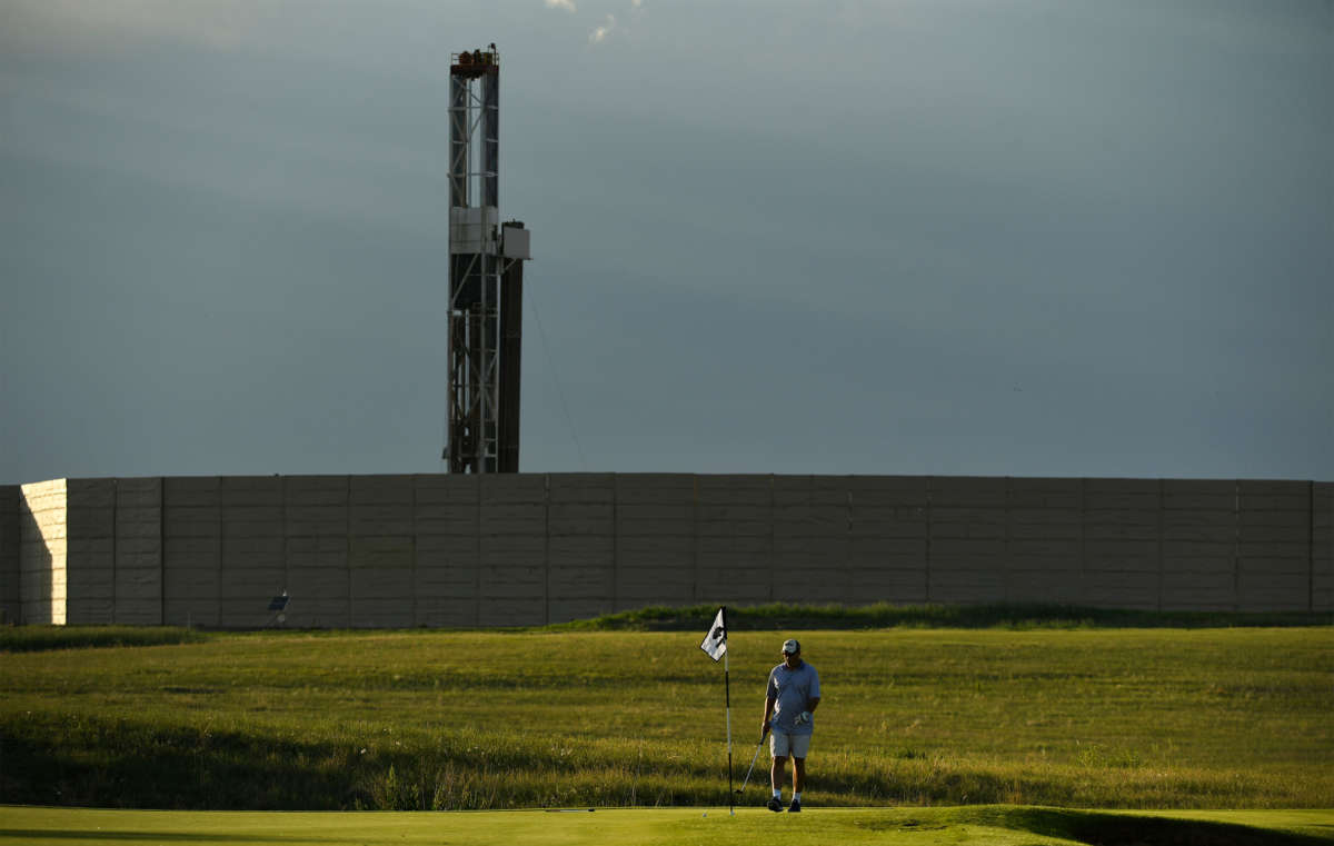 Golfers enjoy playing golf in the late afternoon at Colorado National Golf Course near a drilling operation in the background on June 7, 2017, in Erie, Colorado.