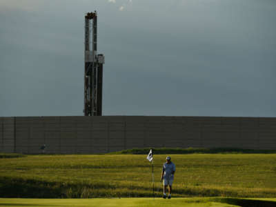 Golfers enjoy playing golf in the late afternoon at Colorado National Golf Course near a drilling operation in the background on June 7, 2017, in Erie, Colorado.