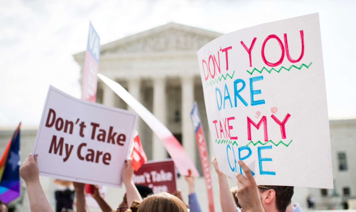 Affordable Care Act supporters hold up signs outside the Supreme Court as they wait for the court's decision on Obamacare on June 25, 2015.