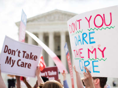Affordable Care Act supporters hold up signs outside the Supreme Court as they wait for the court's decision on Obamacare on June 25, 2015.