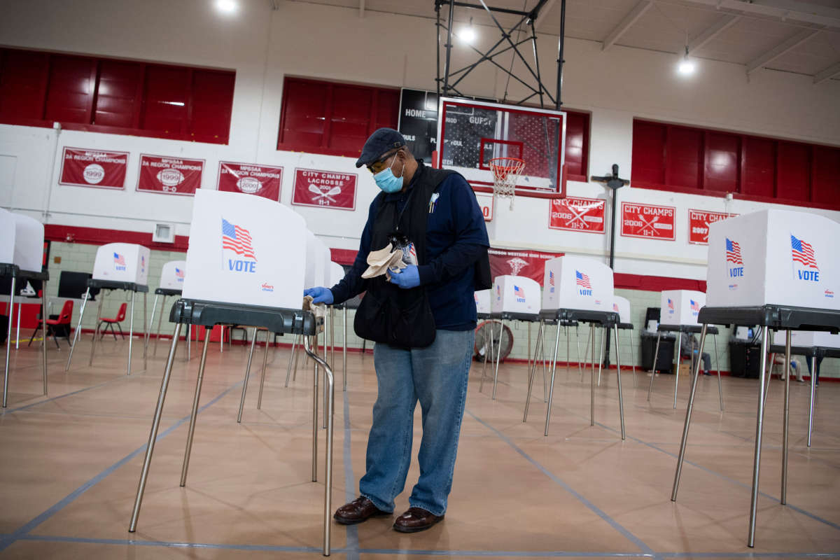 An official disinfects a voting station during the election between Democrat Kweisi Mfume and Republican Kimberly Klacik to fill the remainder of the late Rep. Elijah Cummings term at Edmondson High School in Baltimore, Maryland, on April 28, 2020.