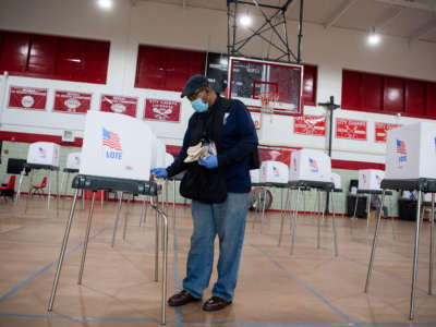An official disinfects a voting station during the election between Democrat Kweisi Mfume and Republican Kimberly Klacik to fill the remainder of the late Rep. Elijah Cummings term at Edmondson High School in Baltimore, Maryland, on April 28, 2020.