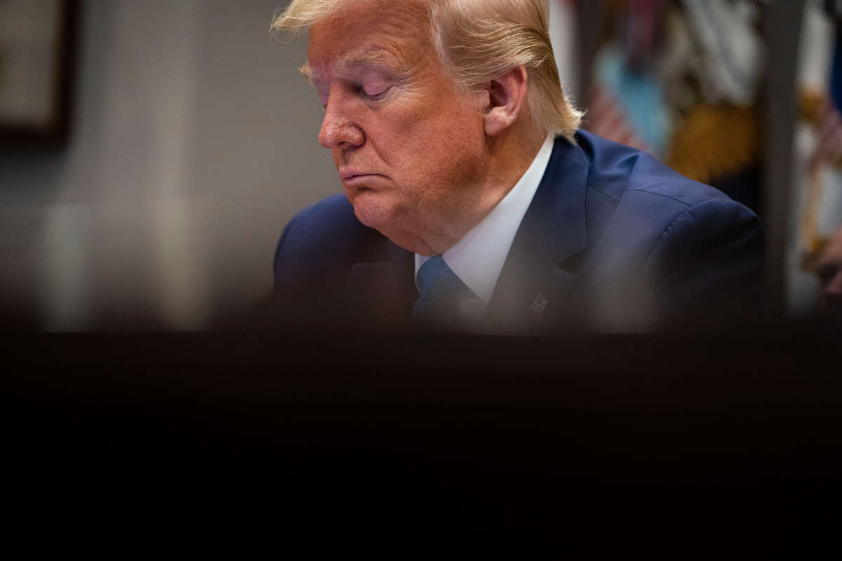 Donald trump sits at a desk