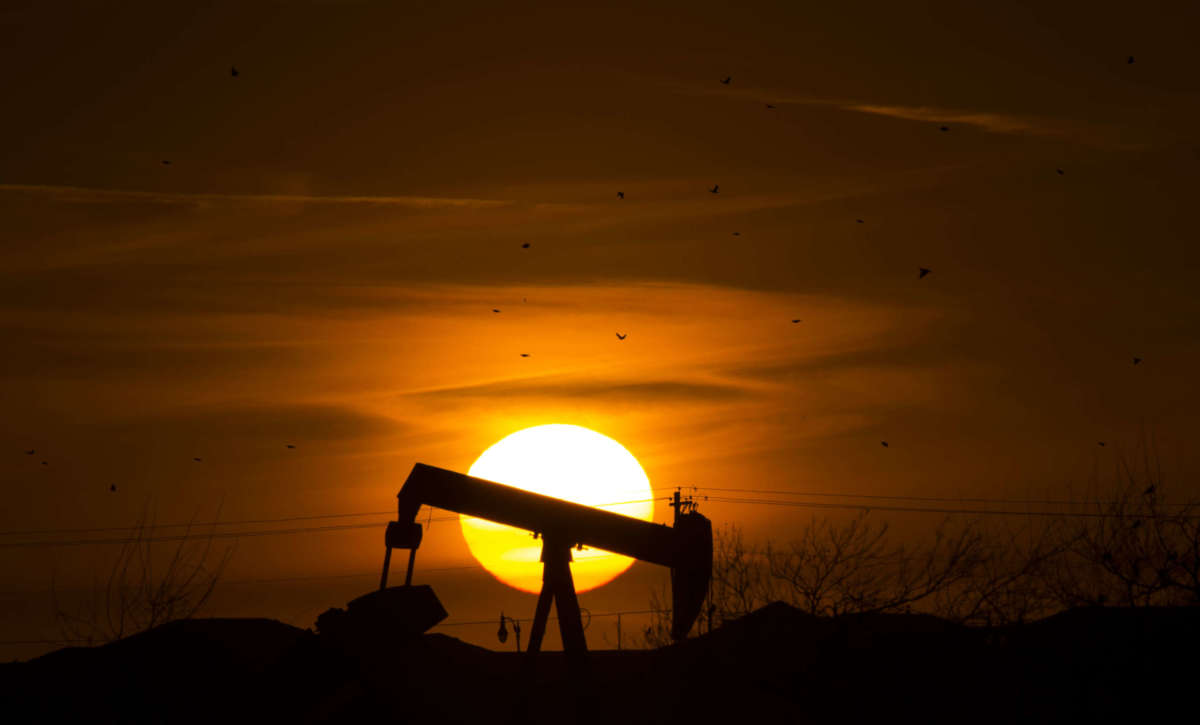 The sun sets behind an old oil well February 20, 2016, in Edmond, Oklahoma.