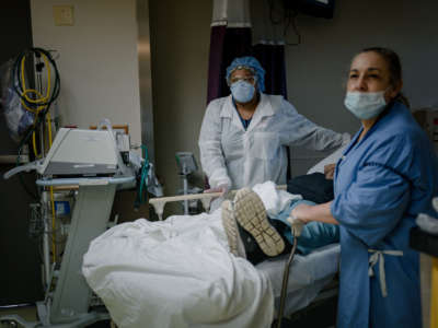 Medical staff in protective gear attend to a patient