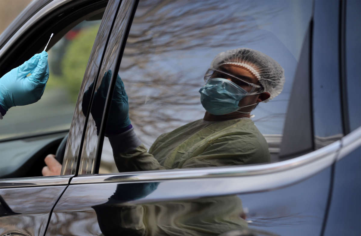 Adrian Santiago takes swabs a patient at the drive-through testing site at Beth Israel Deaconess HealthCare in Chelsea, Massachusetts, on April 29, 2020.