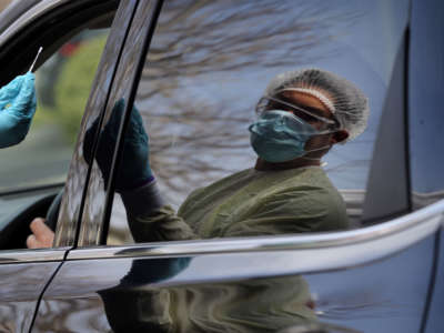 Adrian Santiago takes swabs a patient at the drive-through testing site at Beth Israel Deaconess HealthCare in Chelsea, Massachusetts, on April 29, 2020.