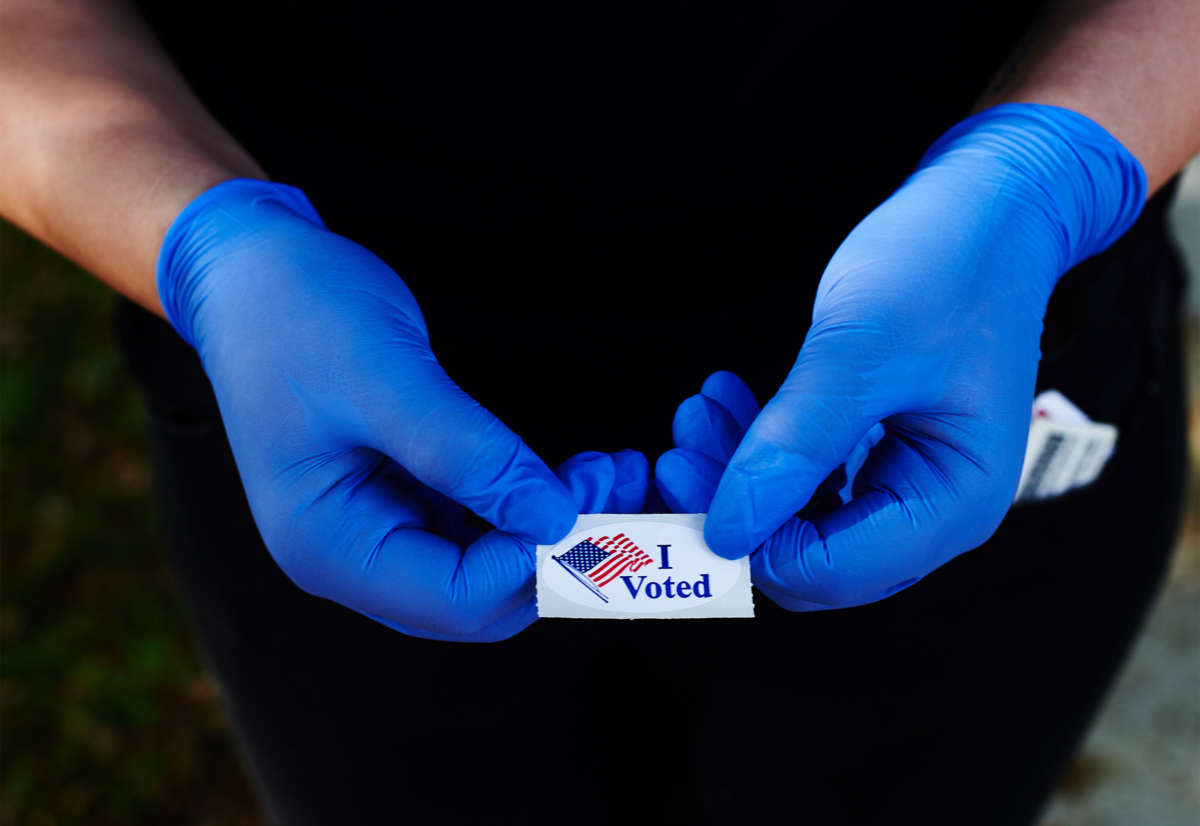 A voter holds an "I Voted" sticker while wearing a pair of rubber gloves after voting in Florida's primary election at the Oldsmar Fire Department voting precinct on March 17, 2020, in Oldsmar, Florida.