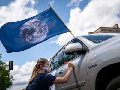 An activist writes messages on her vehicle as she participates in a May Day protest during the coronavirus pandemic, May 1, 2020, Washington, D.C.