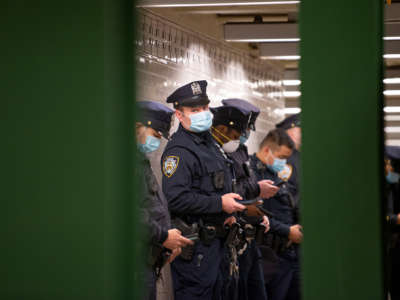 Uniformed police officers disregard social distancing procedures while standing in a group