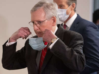 Senate Majority Leader Mitch McConnell removes a mask as he arrives to speak to the media on Capitol Hill in Washington, D.C., May 5, 2020.