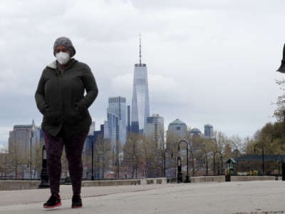 A person in a mask and a jacket walks through new york