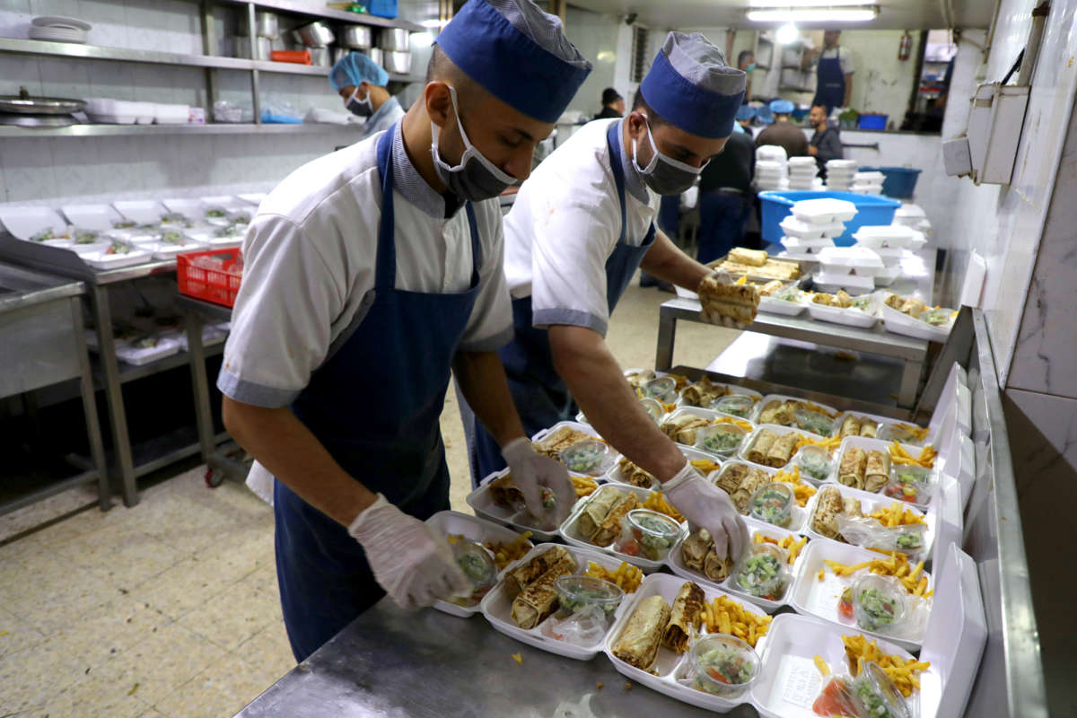 Palestinian chefs prepare meals for the needy in a commercial kitchen