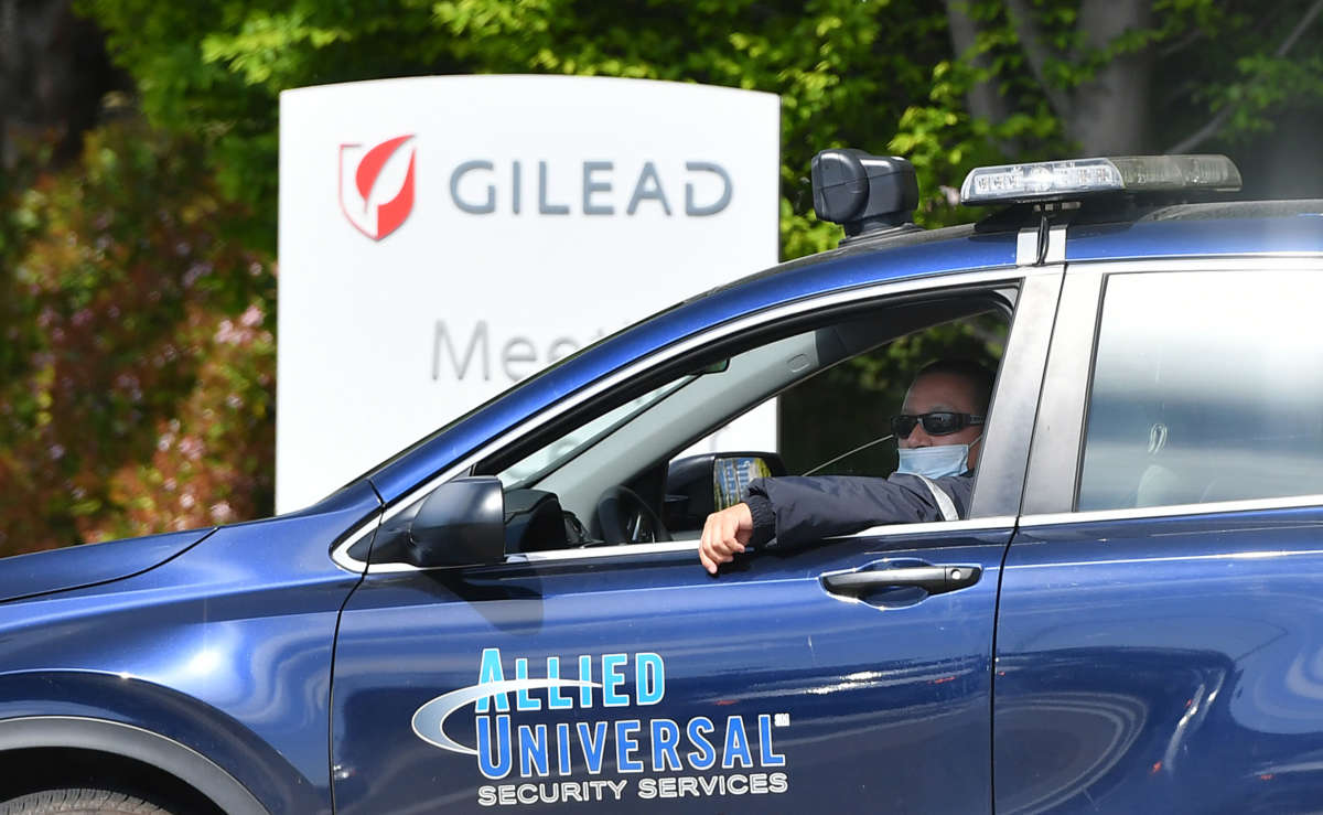 A private security guard wears a mask while sitting in his vehicle in front of the Gilead Sciences headquarters in Foster City, California on April 30, 2020.