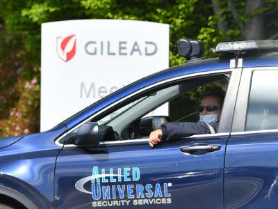 A private security guard wears a mask while sitting in his vehicle in front of the Gilead Sciences headquarters in Foster City, California on April 30, 2020.