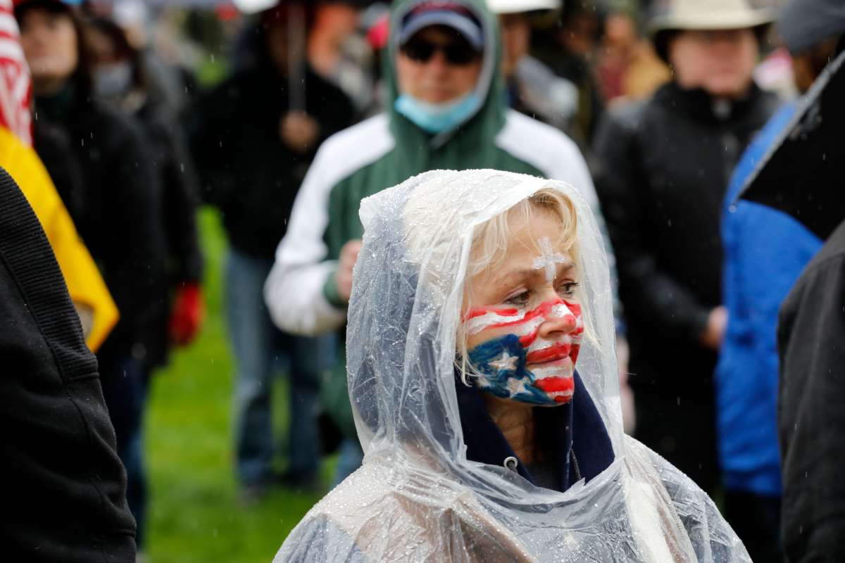 A woman with the u.s. flag painted on her face participates in a reopen protest