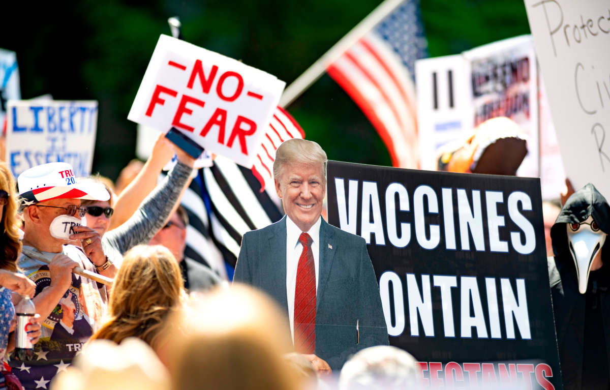 A cardboard cutout of President Trump stands amid people protesting the stay-at-home orders outside the state capitol building in Sacramento, California, on May 1, 2020.