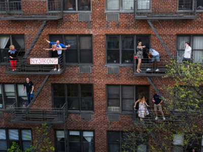 People applaud from their fire escapes to show their gratitude to medical staff and essential workers on the front lines of the coronavirus pandemic during the coronavirus pandemic in the Upper East Side on May 2, 2020, in New York City.