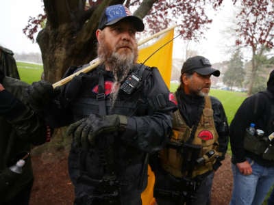 White men with guns and beards display a "don't tread on me" flag during a protest
