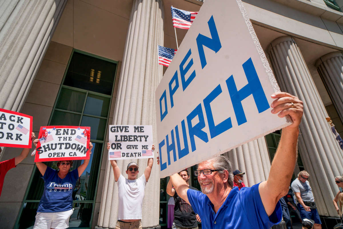 Demonstrators hold signs demanding their church to reopen, protest during a rally to reopen California and against stay-at-home directives on May 1, 2020, in San Diego, California.