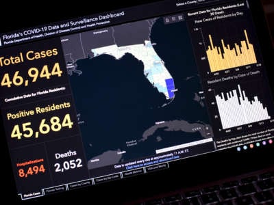 A laptop displays a COVID tracking app for Florida