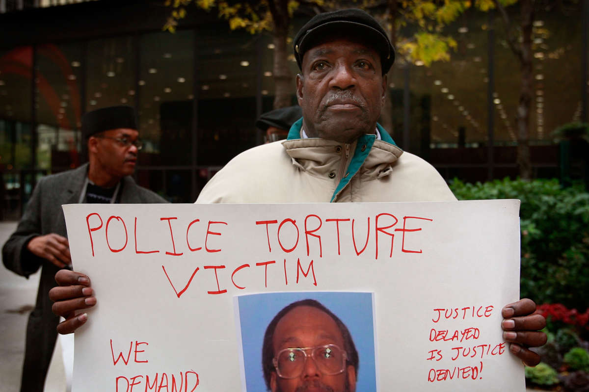 Aaron Cheney demonstrates outside the federal courthouse where former Chicago Police Commander Jon Burge was attending a hearing on charges he obstructed justice and committed perjury for lying while under oath during a 2003 civil trial about decades-old Chicago police torture allegations October 27, 2008, in Chicago, Illinois.