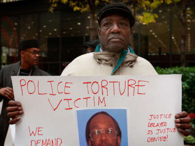 Aaron Cheney demonstrates outside the federal courthouse where former Chicago Police Commander Jon Burge was attending a hearing on charges he obstructed justice and committed perjury for lying while under oath during a 2003 civil trial about decades-old Chicago police torture allegations October 27, 2008, in Chicago, Illinois.