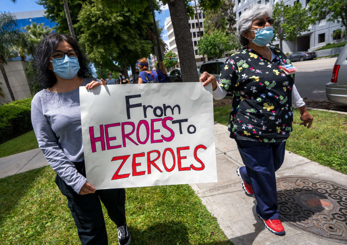 Health care workers hold a placard that says "From Heroes to Zeroes" during a protest against hospital under-staffing and insufficient personal protective equipment for doctors and nurses treating COVID 19 patients amid the coronavirus pandemic, outside Saint Joseph Medical Center hospital in Burbank, California, May 19, 2020.
