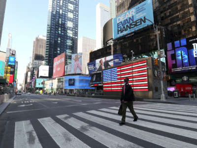 An improperrly-masked man walks across a deserted Time Square