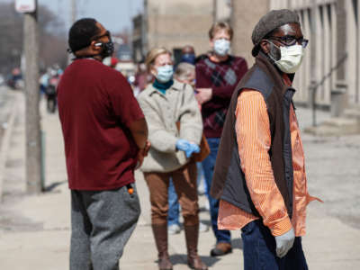 Residents wait in a long line to vote in a presidential primary election outside the Riverside High School in Milwaukee, Wisconsin, on April 7, 2020.