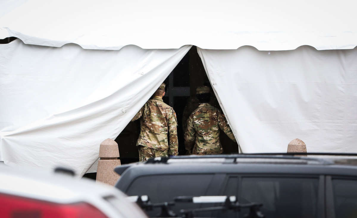 Military personnel step out of a tent set up at the back entrance to the Holyoke Soldiers home in Holyoke, Massachusetts, on March 3, 2020. Forty-seven had died of the virus at the state-run home for veterans as of April 17.