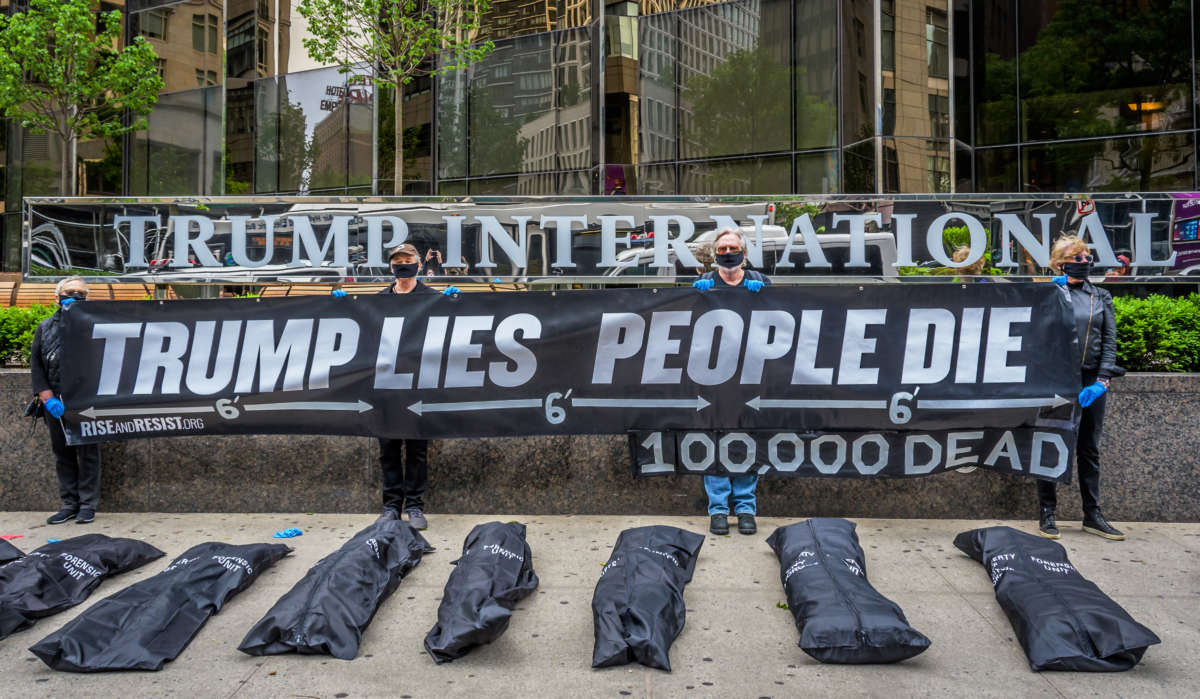 Activists hold a banner that reads: TRUMP LIES, PEOPLE DIE and 100,000 DEAD behind body bags placed outside Trump International Hotel and Tower in New York City, May 24, 2020.