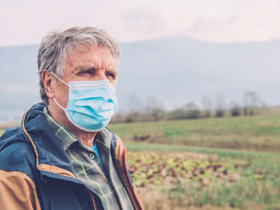 A rural man wears a face mask amidst his field of crops