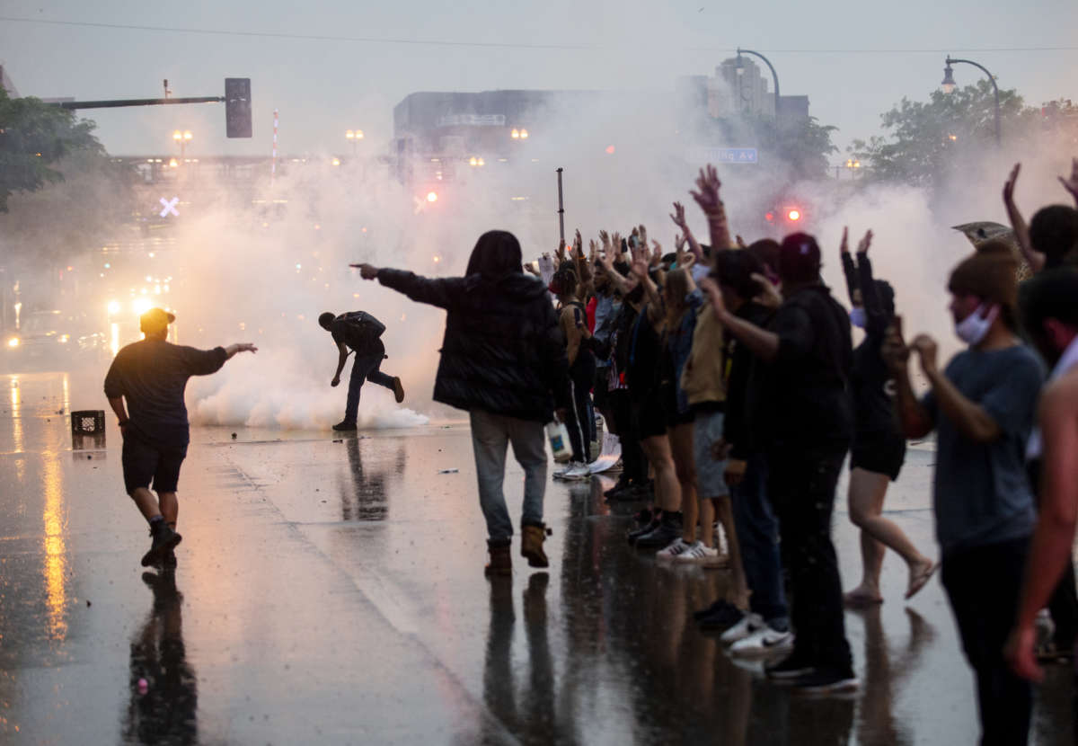 Peaceful protesters raise their hands as they're attacked with tear gas by the minneapolis police department