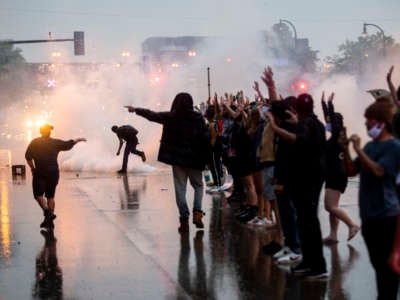 Peaceful protesters raise their hands as they're attacked with tear gas by the minneapolis police department